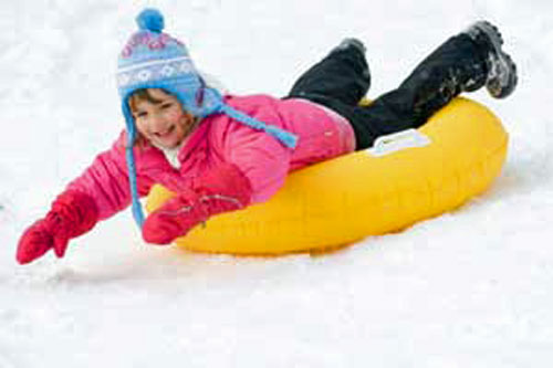 Photo of child sliding down snow hill on inner tube